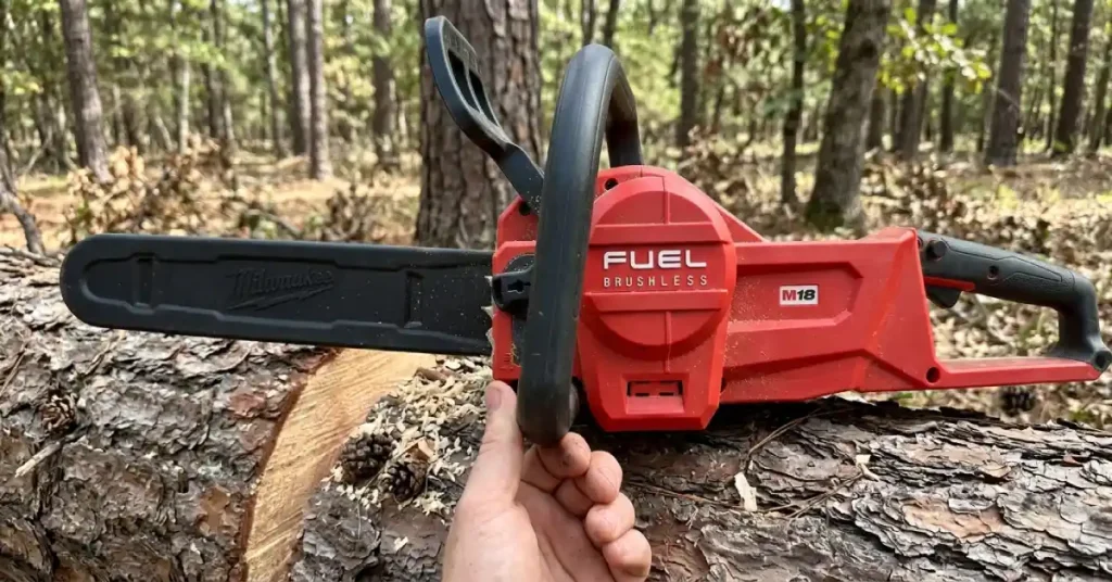 Hand holding a Milwaukee M18 Fuel chainsaw resting on a log.
